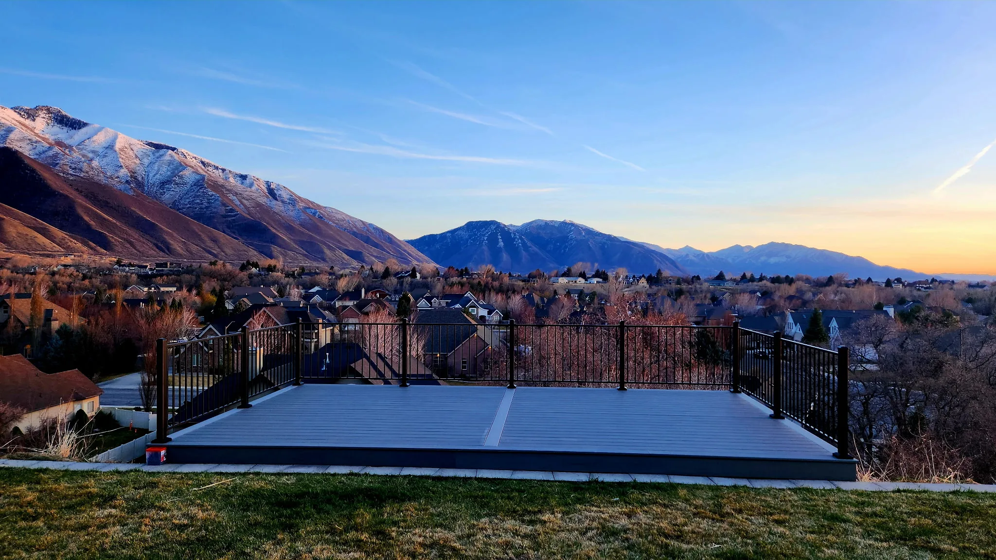 Modern elevated composite deck with black railing overlooking Utah mountains at sunset