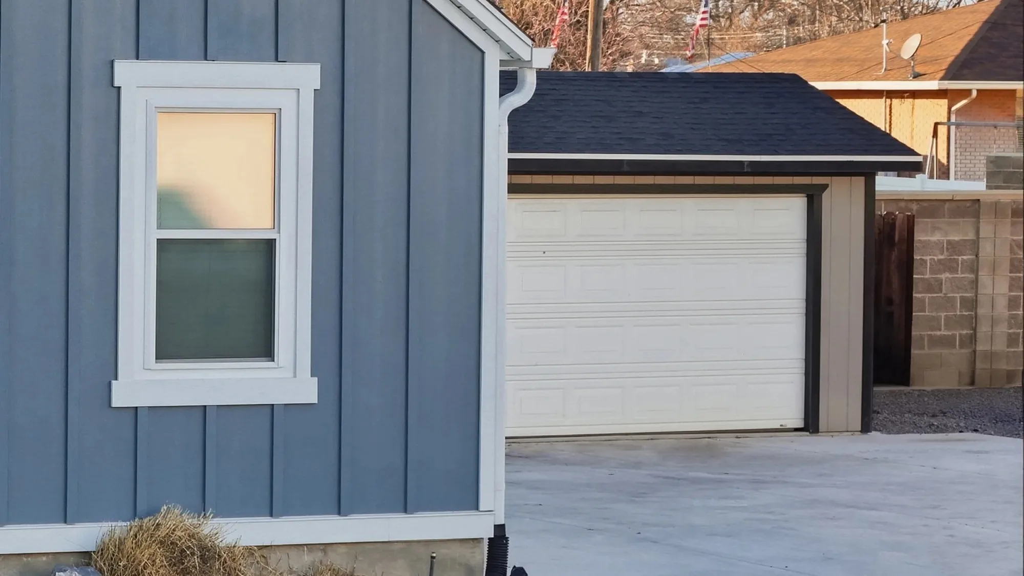 Complete white sectional garage door on a detached garage with a concrete driveway